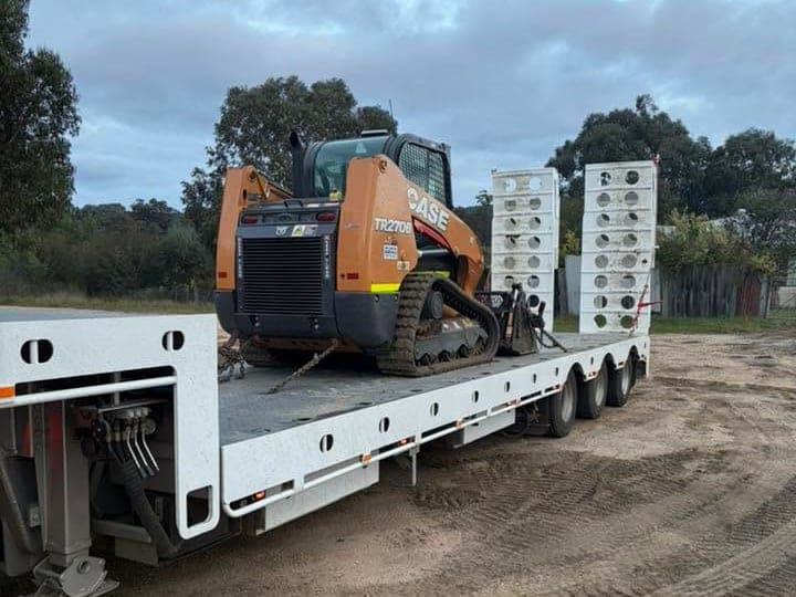 Drop deck widener loaded with an excavator